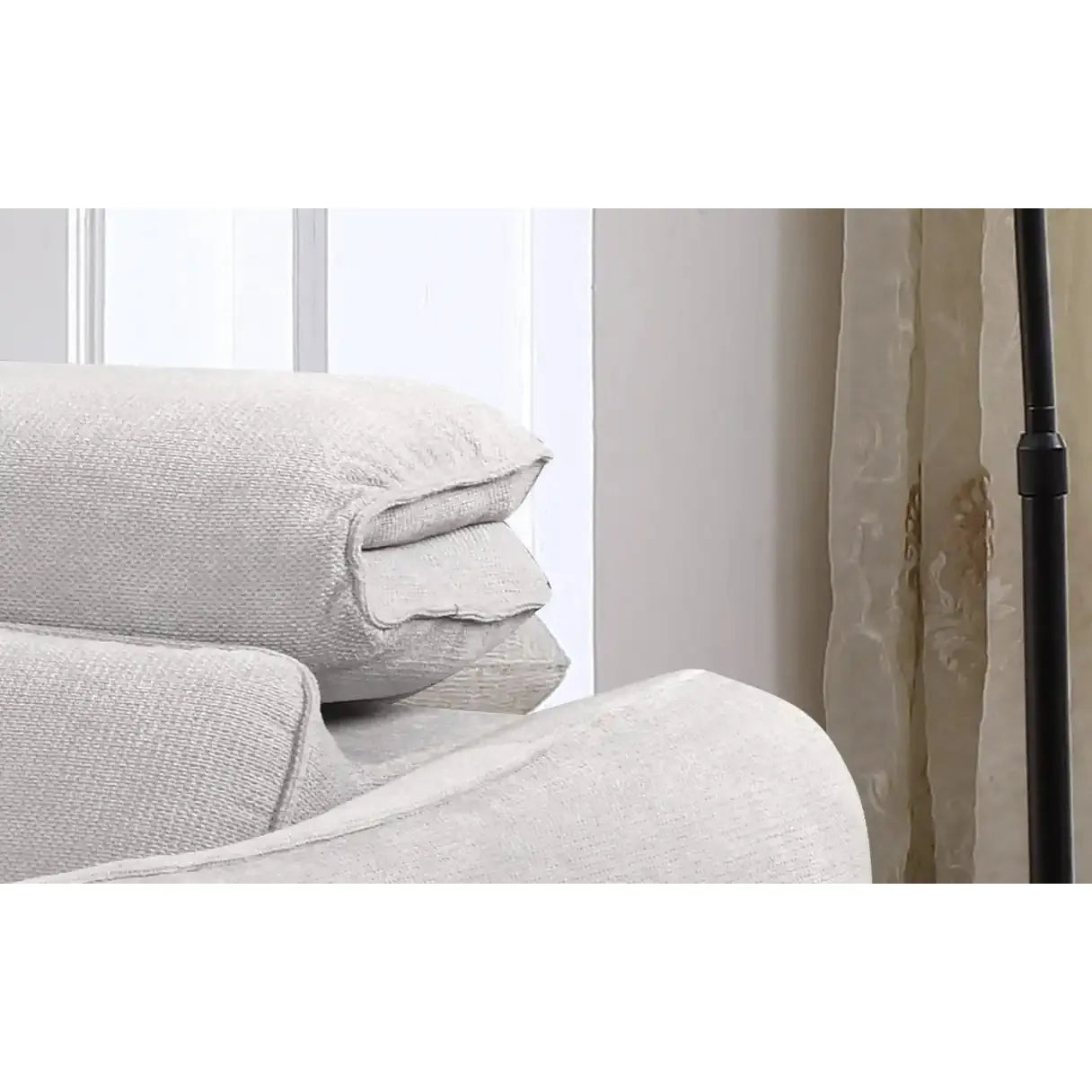 Stack of light gray textured pillows on a white surface with a neutral background