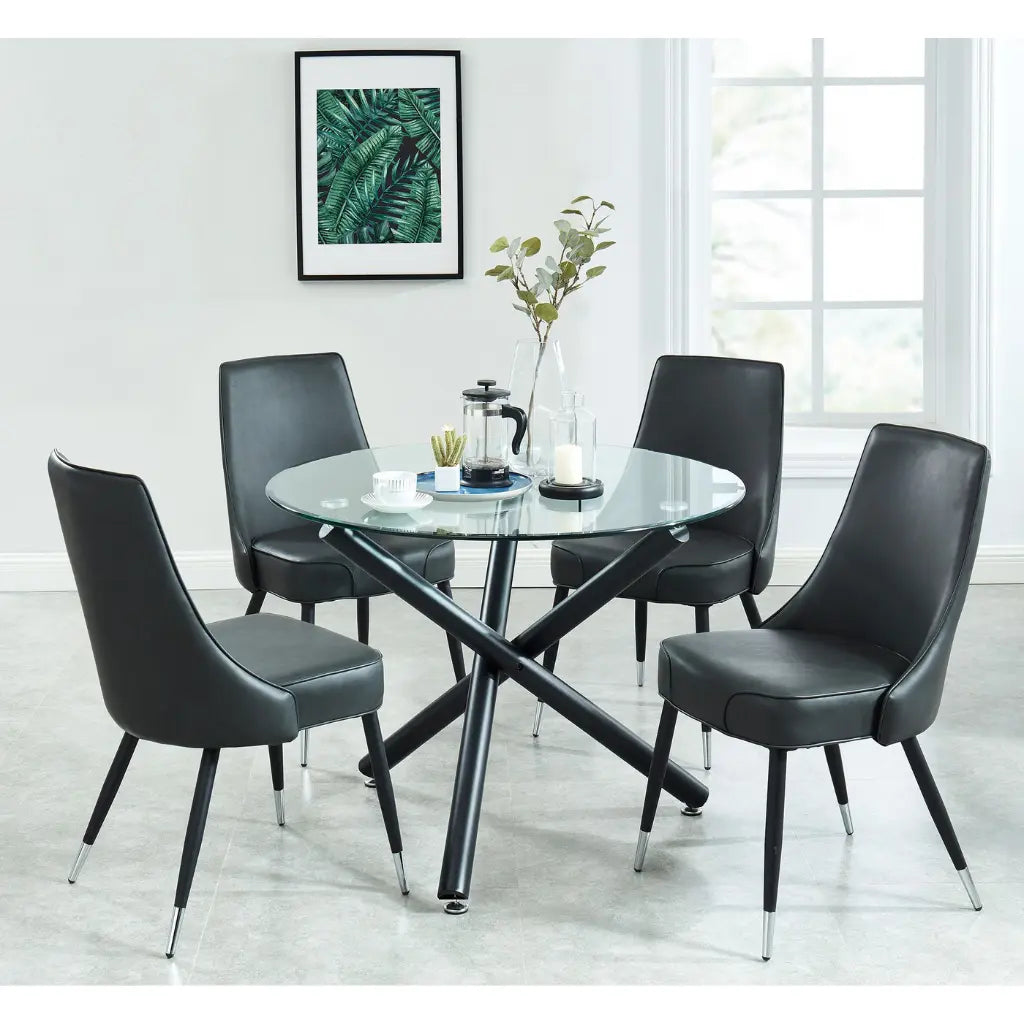 Dining room setup with a round glass table and four black chairs.