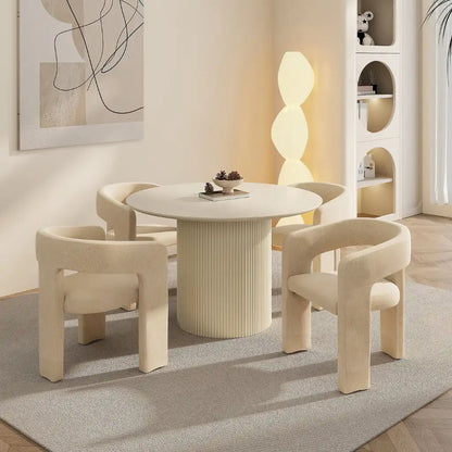 Modern dining room with a round table and four chairs in a stylish interior setting.