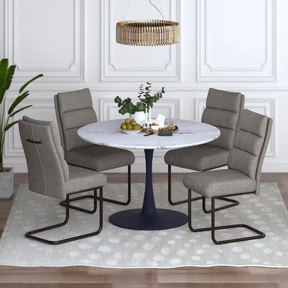 Dining room setup with a round table and four gray chairs in a well-lit room.