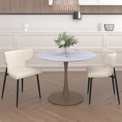 Round dining table with marble top and four white chairs in a room with wooden flooring and white walls.